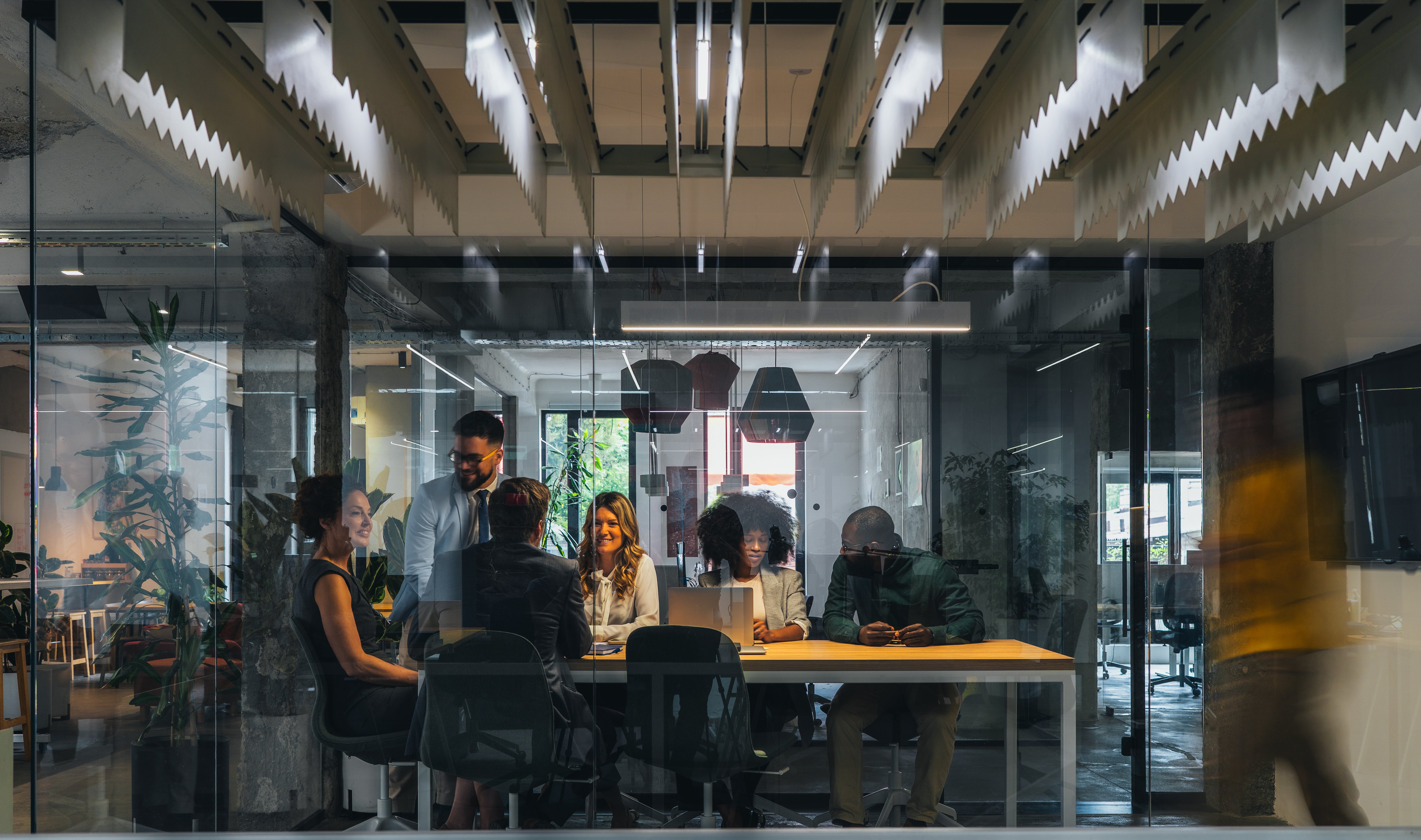 Office colleagues speak around a work table