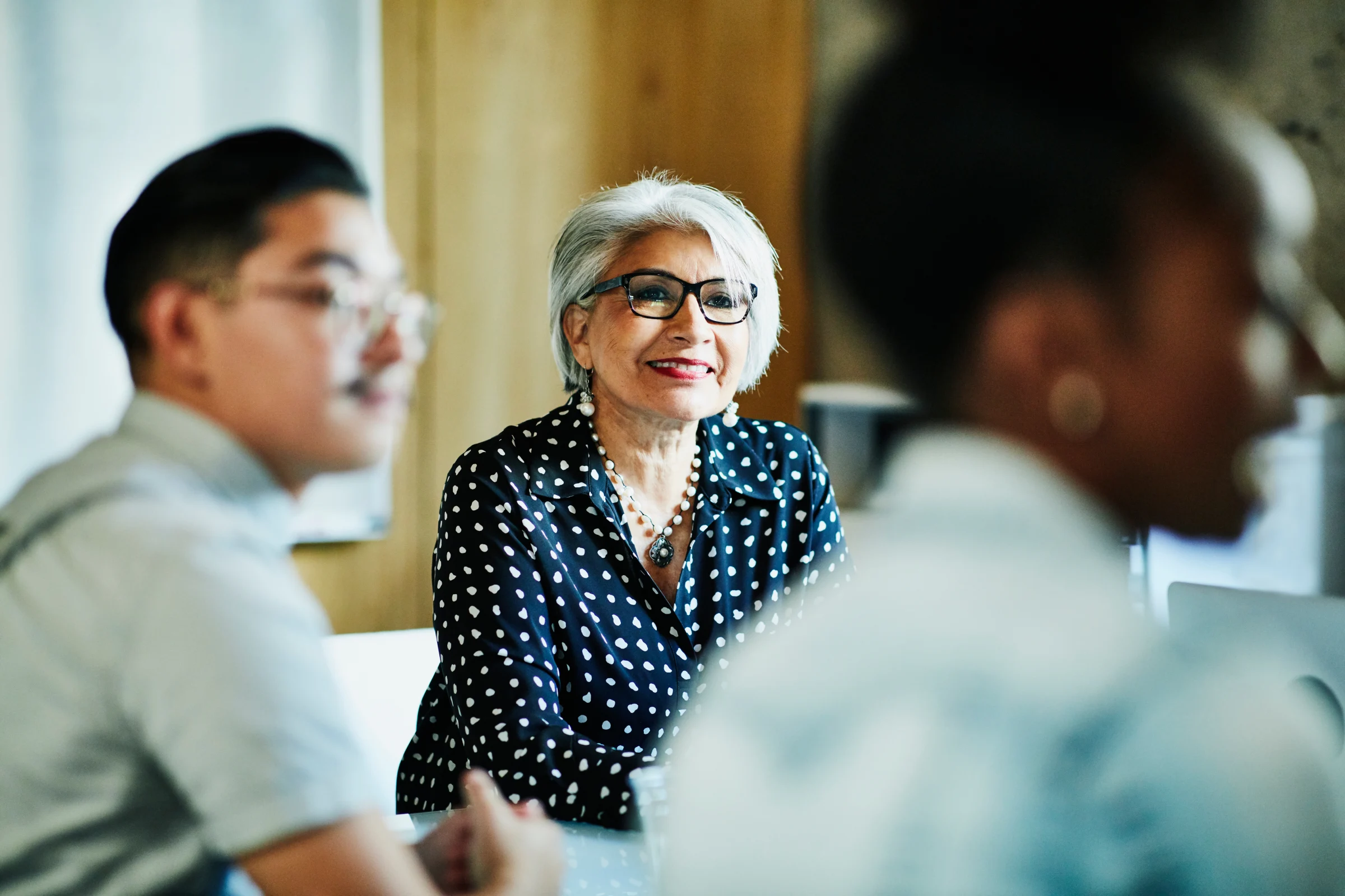 A woman engages with other colleagues at a meeting