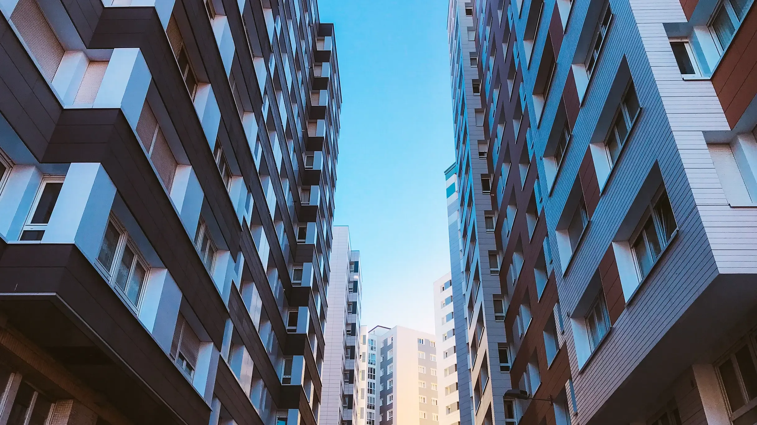 Low-angle view looking up at modern high-rise apartment buildings.
