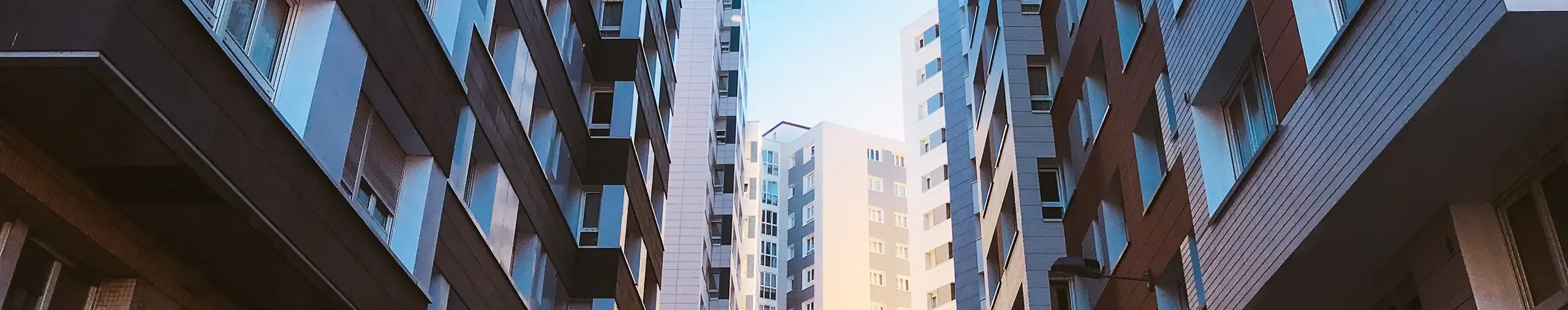 Low-angle view looking up at modern high-rise apartment buildings.